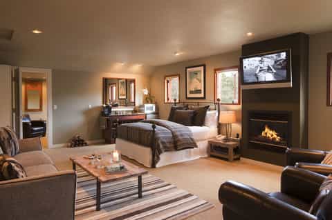 Luxury hotel bedroom suite with fireplace, flat-screen TV, spa-like bathroom, and elegant furnishings