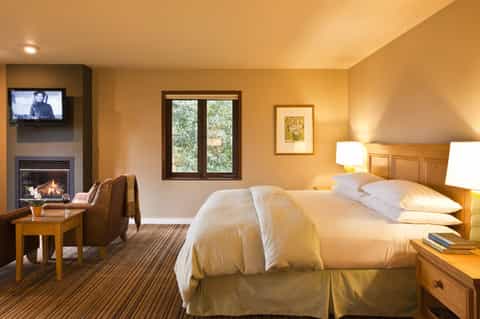 Luxurious hotel bedroom with fireplace, warm lighting, wooden headboard, and comfortable furnishings