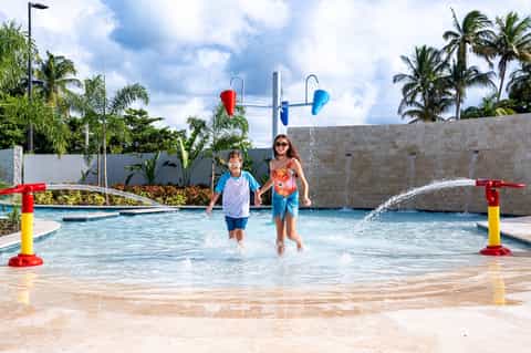 Children playing in shallow resort pool with colorful water play features