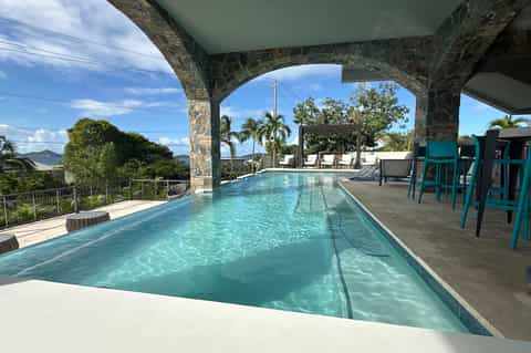 Lap pool under covered structure with mountain and tropical landscape views