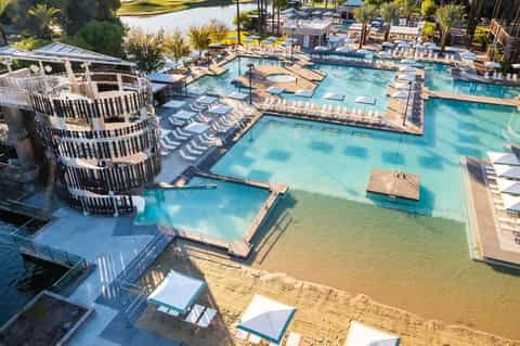 Multiple connected pools with turquoise water, lounge chairs, and waterfront buildings