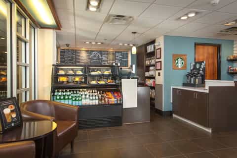 Modern cafe interior with Starbucks branding, pastry display case, and comfortable seating