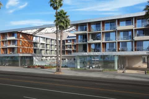 Modern Shore Hotel exterior with multi-story building, palm trees, and street-level entrance