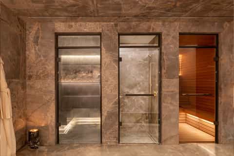 Spa facility with marble walls, glass shower doors, and wooden sauna entrance