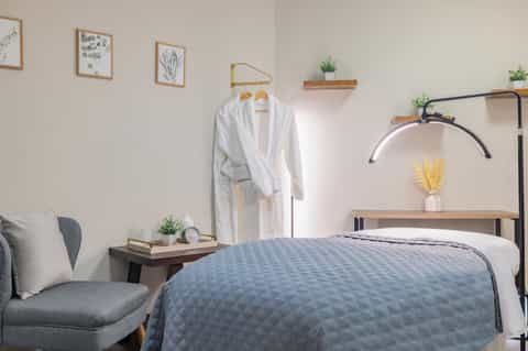 Minimalist bedroom with metal frame bed, wooden nightstand, and botanical wall art