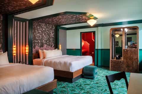 Luxury hotel bedroom with canopy bed, teal accents, and ornate patterned headboard