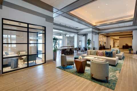 Spacious resort lobby with wood flooring, modern seating, and glass partitions