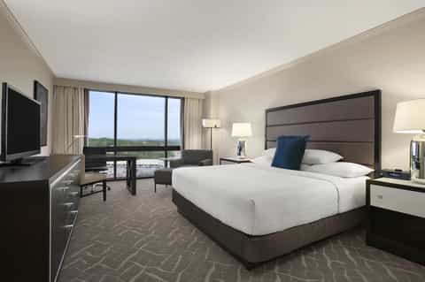 Modern hotel bedroom with king bed, flat-screen TV, and expansive window views