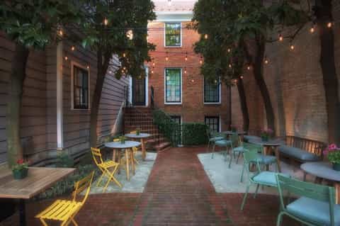 Brick courtyard with yellow and green chairs, string lights, and ivy-covered brick buildings