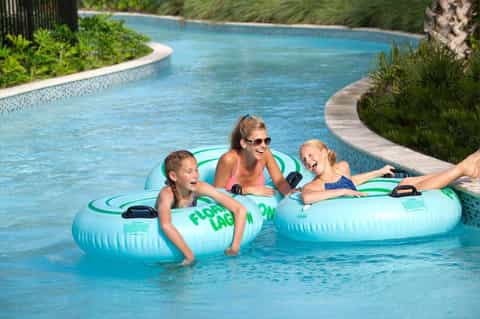 Family enjoying lazy river ride on inflatable tubes in tropical resort pool