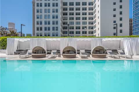 Rooftop pool area with turquoise water, white cabanas, and curved privacy curtains