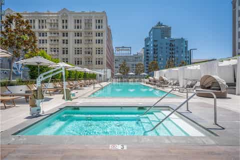 Urban rooftop pool with lounge chairs, white umbrellas, and historic downtown architecture backdrop