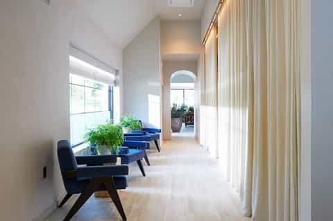 Bright hallway with blue accent chairs, natural light, and archway leading to additional seating
