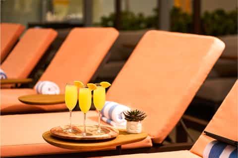 Poolside lounge chairs with orange cushions and welcome drinks