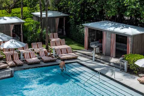Luxury resort pool surrounded by striped lounge chairs and private cabanas in tropical setting