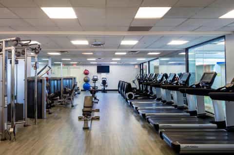 Full-service gym with treadmills, stationary bikes, weight machines, and exercise equipment arranged throughout the space.