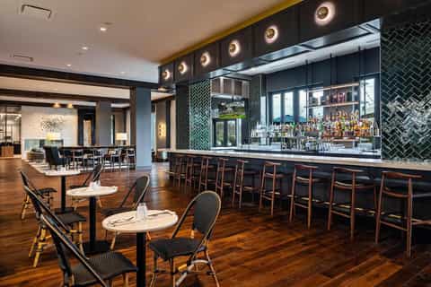 Contemporary bar and restaurant with dark green tile backsplash, wooden seating, and ambient lighting