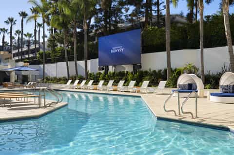 Resort pool with cabana seating, lounge chairs, palm trees, and Marriott Bonvoy signage