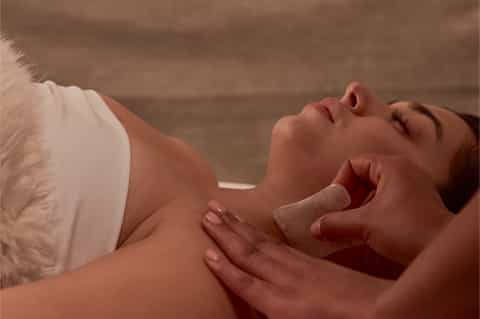 Woman receiving facial massage treatment at spa with soft lighting