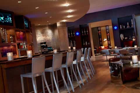 Upscale lounge bar with wood accents, modern lighting, and display shelving