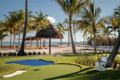 Scenic beach resort with mini golf course, tiki huts, palm trees, and ocean view