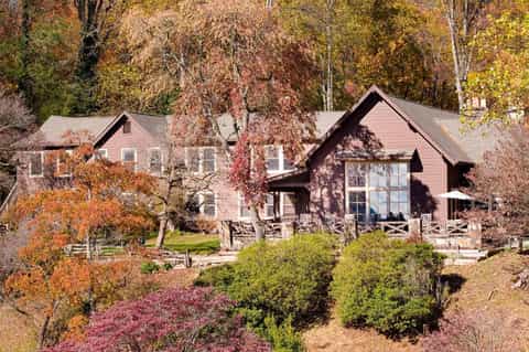 Residential house with autumn foliage, pink siding, white trim, and manicured landscaping