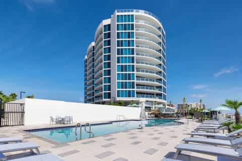 Beachfront high-rise hotel tower with curved balconies and swimming pool area below