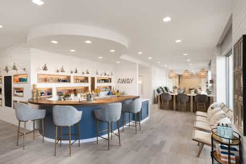 Bright wellness spa reception with curved blue desk, white shiplap walls, and comfortable seating area