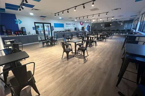 Modern cafe interior with blue accent walls, wooden floors, counter service, and dining tables