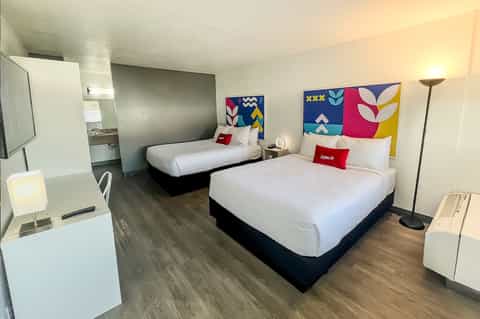 Modern hotel room with two queen beds, colorful geometric headboards, and contemporary furnishings