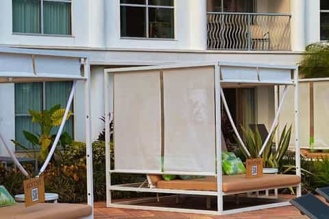Modern poolside lounge beds with white frame and beige fabric under sun shades