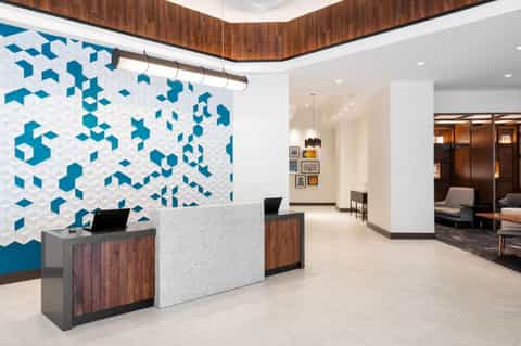 Modern hotel reception desk with geometric blue tile accent wall and wooden ceiling details