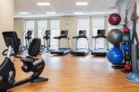Modern fitness center with treadmills, stationary bikes, exercise balls, bright windows