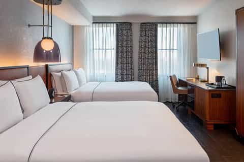 Hotel room with two beds, hanging pendant light, and patterned curtains