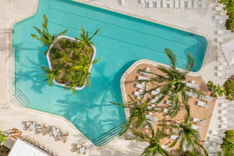 Aerial view of turquoise pool with palm tree islands and wooden deck loungers