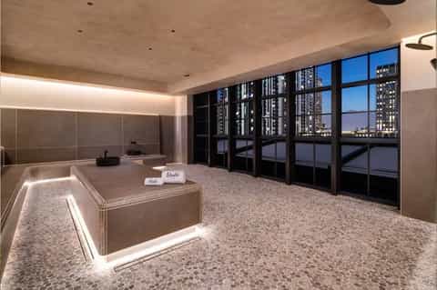 Luxury spa with soaking tub, floor-to-ceiling windows overlooking city skyline at dusk