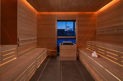 Luxury spa sauna with wooden interior, ambient lighting, and city skyline view through windows