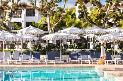 Resort pool with white scalloped umbrellas, lounge chairs, and Mediterranean-style architecture