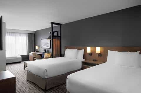 Modern hotel room with two beds, wood headboards, and contemporary decor