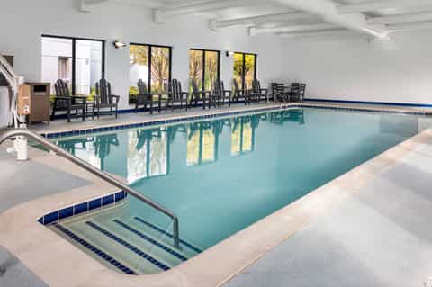 Indoor heated pool with Adirondack chairs, spa hot tub, and large windows