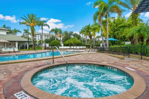 Circular hot tub with palm trees and resort buildings under blue sky