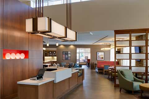 Modern hotel lobby with wood accents, reception desk, contemporary furniture, and open layout design