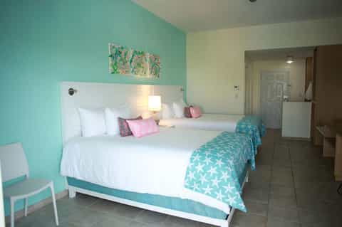 Hotel guest room with two queen beds, turquoise walls, and modern furnishings