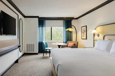 Modern hotel bedroom with dual queen beds, sitting area, and flat-screen TV