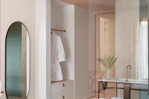 Modern bathroom featuring white subway tile, arched mirror, glass shower enclosure, and natural light