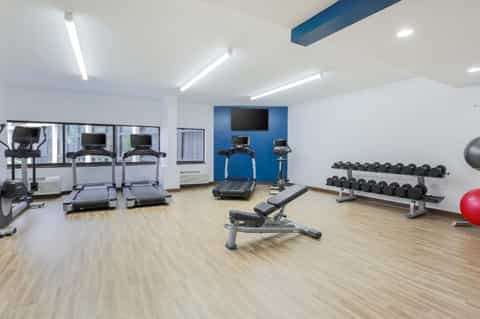 Fitness center with treadmills, exercise bikes, weights, and blue accent wall
