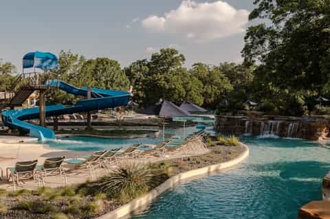 Water park with blue spiral slide, lazy river, and natural spring setting surrounded by trees