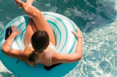 Woman floating on turquoise striped pool float in crystal clear tropical ocean water