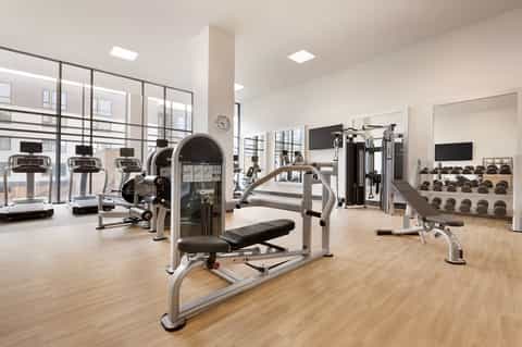Contemporary fitness center with cardio machines, weights, and floor-to-ceiling windows