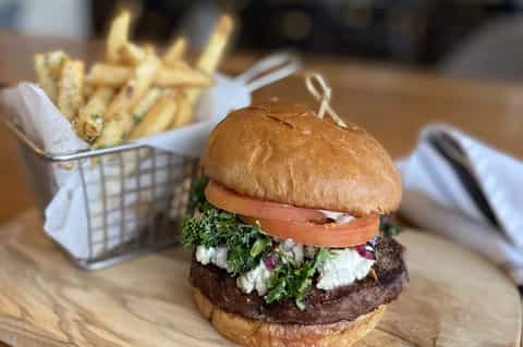 Gourmet burger with kale, tomato, and feta cheese served with french fries